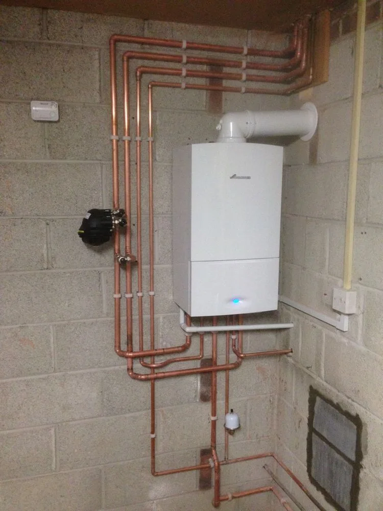 Wall-mounted boiler with neatly routed copper pipework by Scott Plumbing and Heating